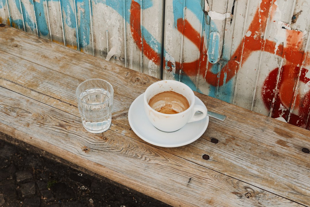 Specialty Coffee Berlin: Espresso und Wasserglas auf einer Holzbank vor einer Graffitiwand