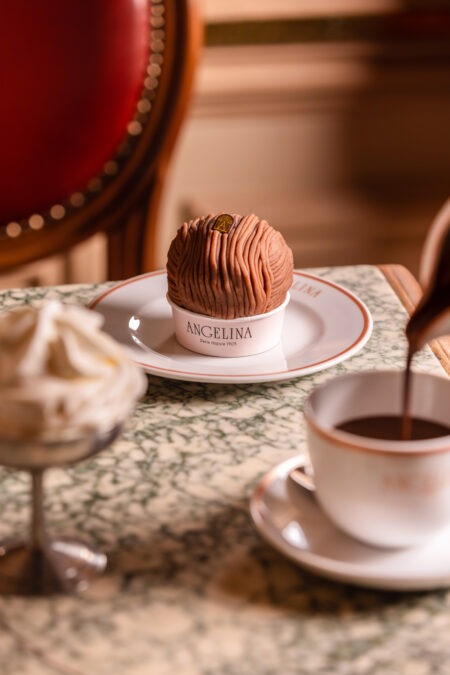 Mont-Blanc von Angelina auf einem Teller, daneben wird Trinkschokolade in eine Tasse gegossen, links Schlagsahne im Glas