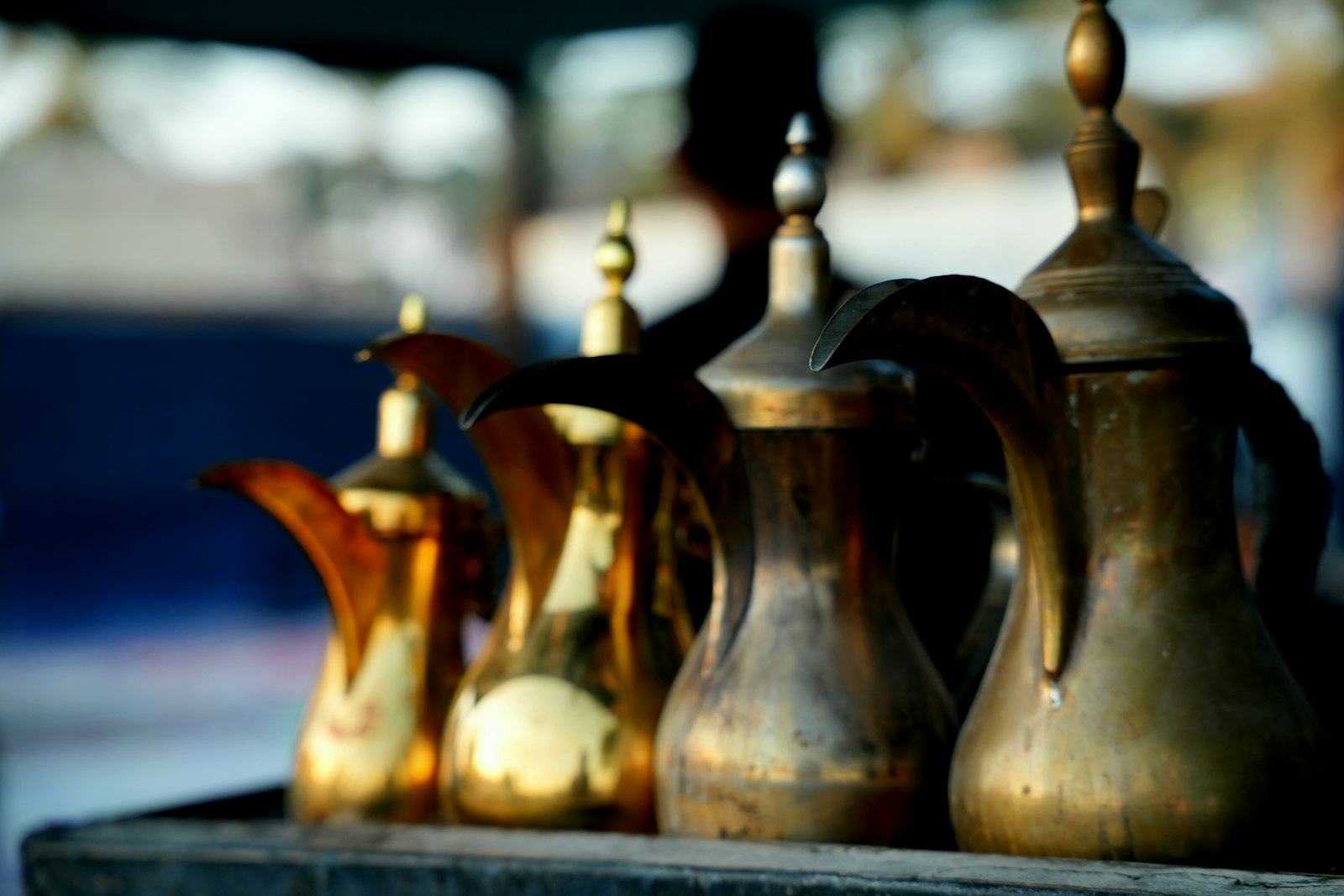 Vier traditionelle arabische Kaffeekannen aus Messing nebeneinander auf Holz