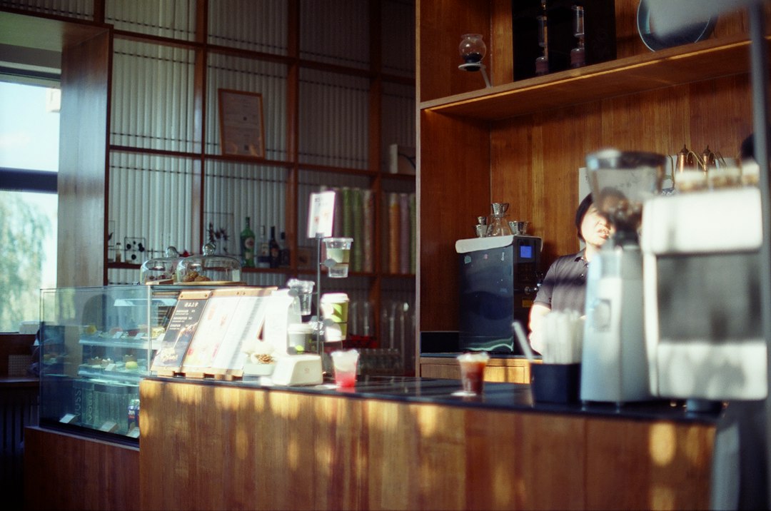 Barista hinter einem Kaffeetresen mit Getränken und Gebäck