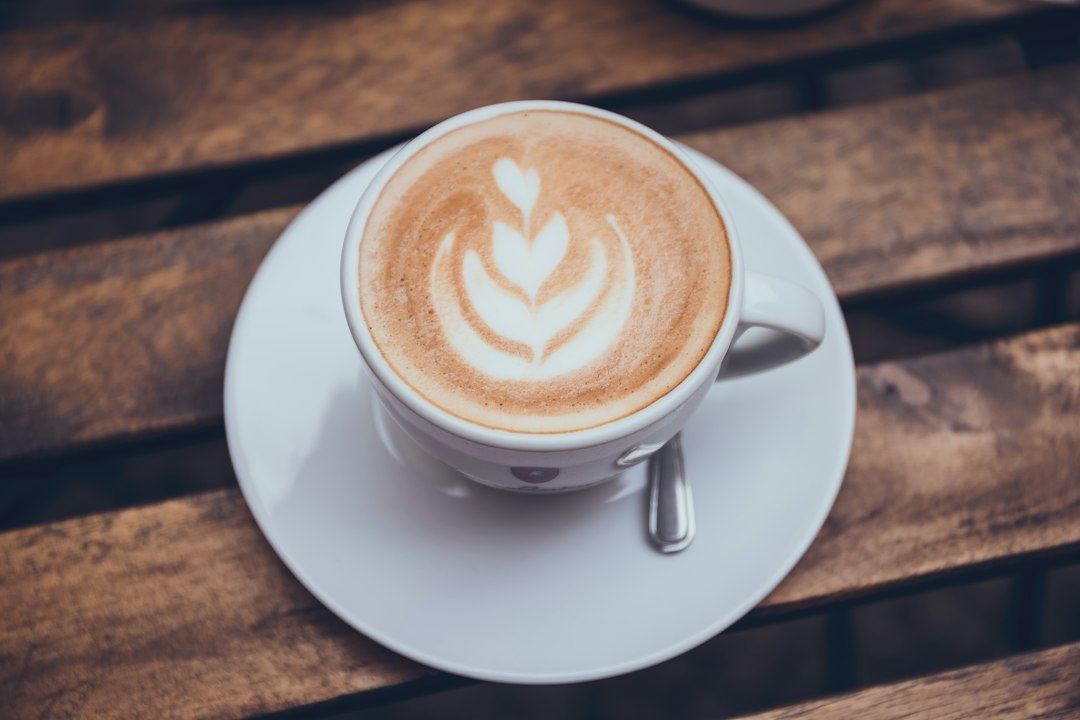 Cappuccino in einer Tasse auf Untertasse, auf einem Holztisch