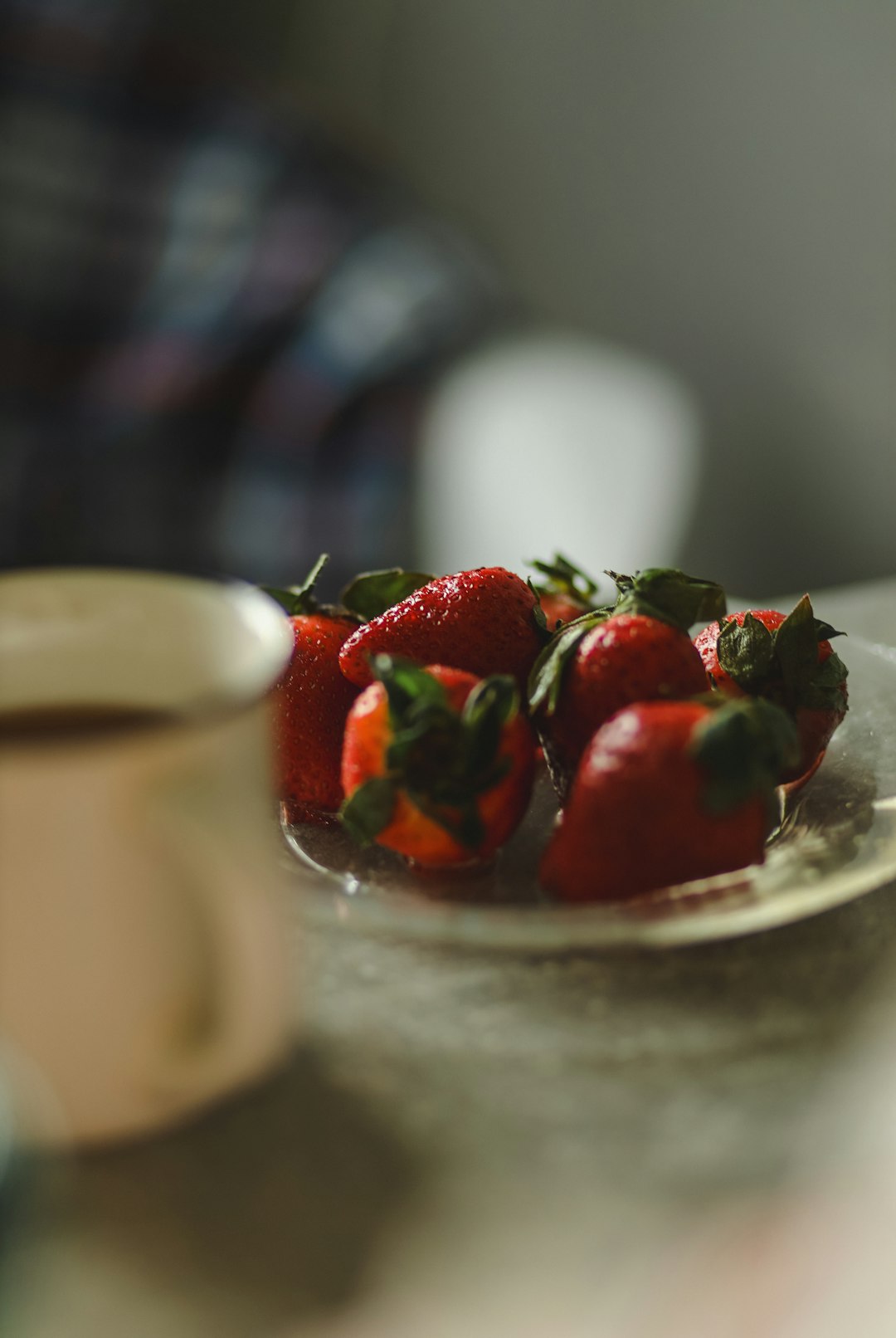 Teller mit frischen Erdbeeren neben einer Tasse Kaffee; Erdbeere ist eine typische Frucht bei der Co-Fermentation