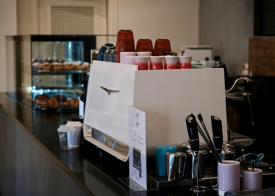 Espresso machine with cups on a café counter, pastries in the background