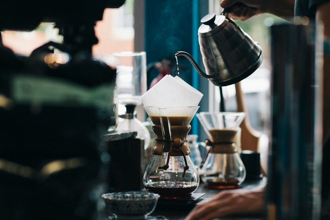 Coffee being brewed by hand and running into a glass carafe
