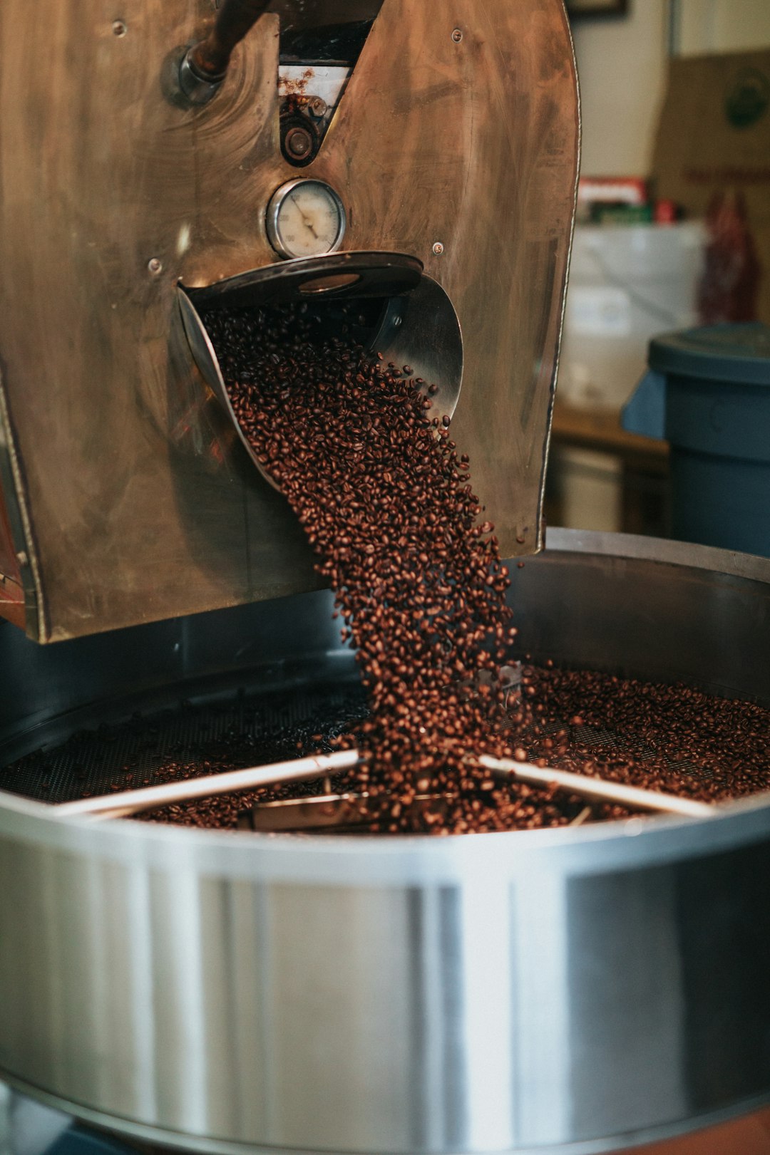 Geröstete braune Kaffeebohnen in einem runden Behälter; die Röstung ist die vorletzte Station der Kaffeeherstellung