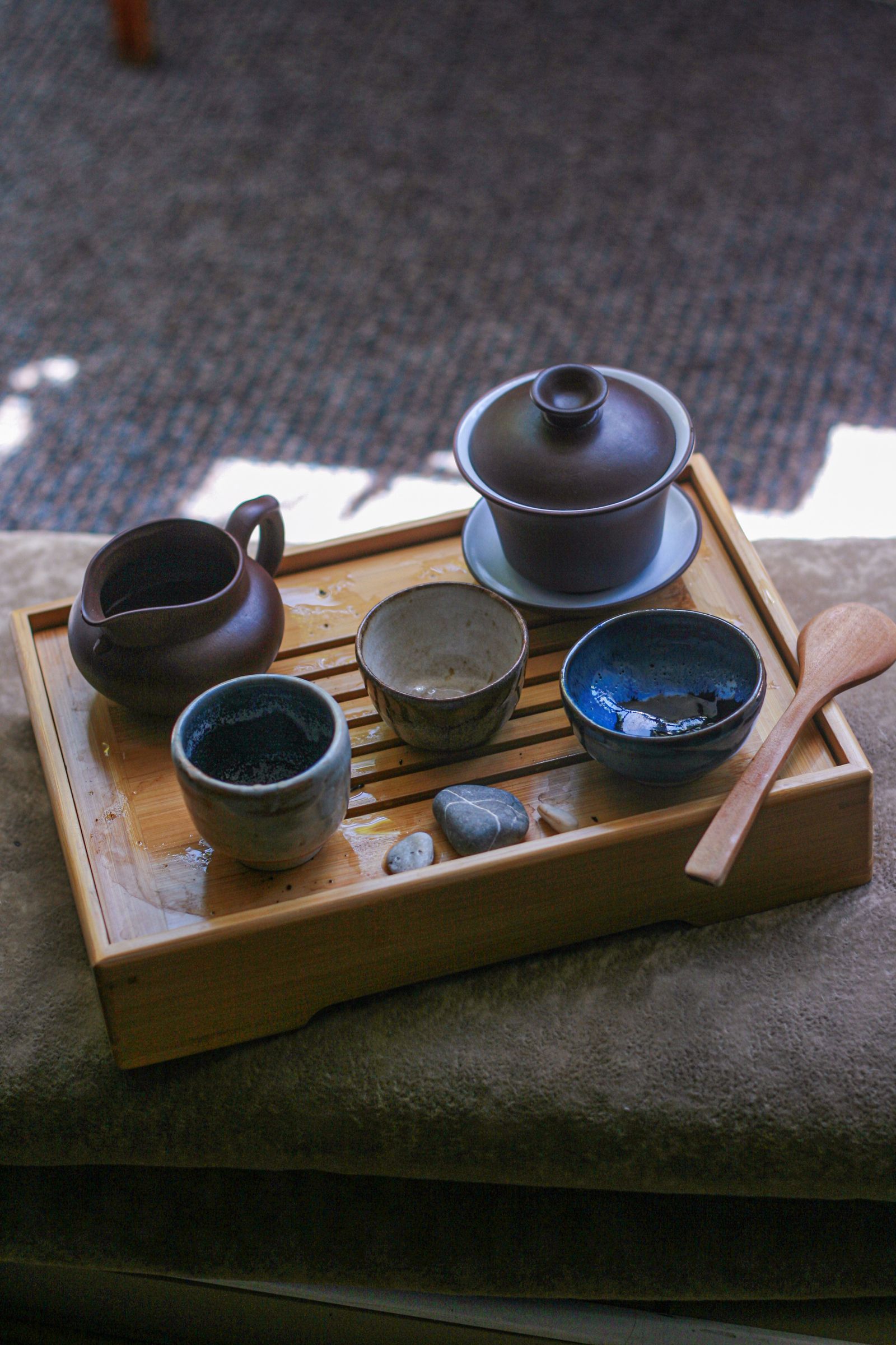 Gongfu-Cha-Teeservice auf einem Holztablett: Gaiwan, Ausgießkännchen und drei kleine Teeschalen