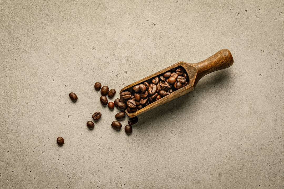 Wooden scoop full of coffee beans on a light stone surface