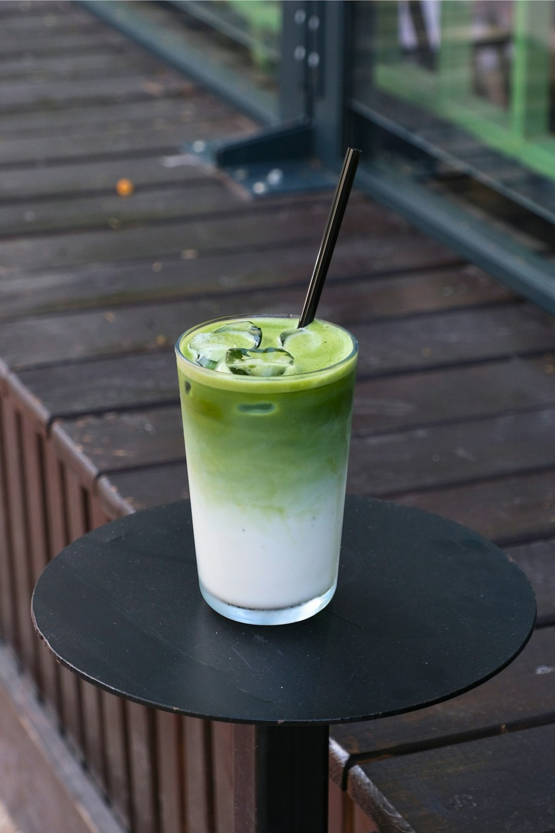 Iced Matcha Latte mit Eiswürfeln im Glas auf einem schwarzen Tisch