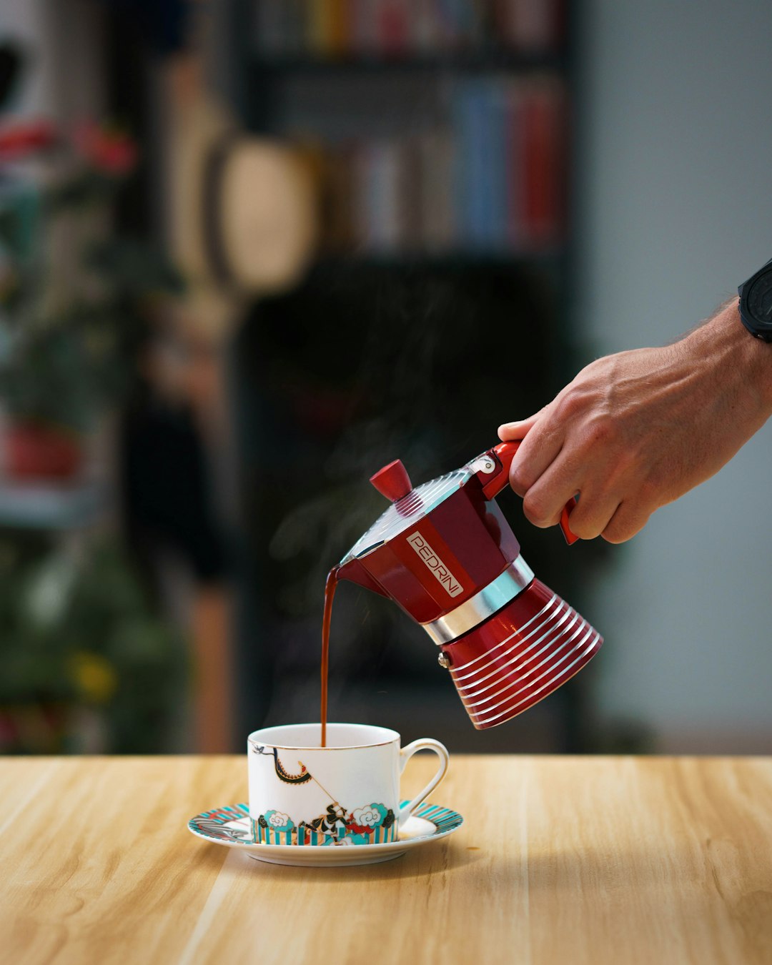 Frisch gebrühter Kaffee aus der Moka-Kanne wird in eine Tasse gegossen