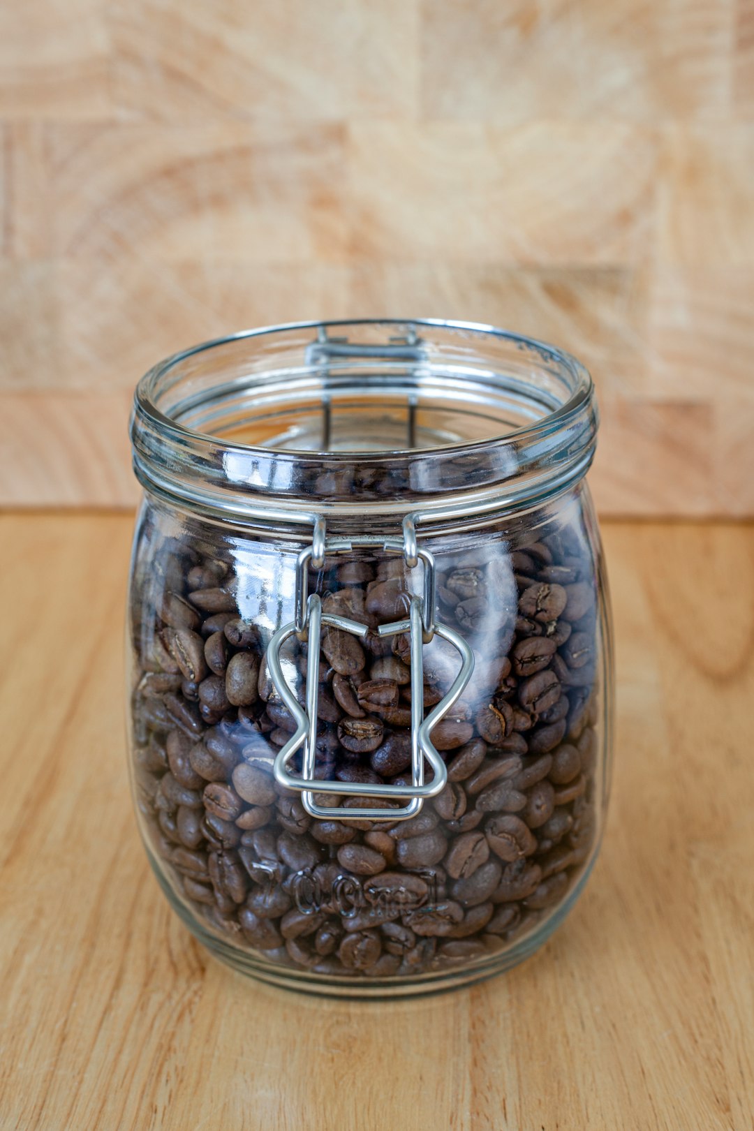 Kaffee lagern: geöffnetes Glas mit gerösteten Kaffeebohnen auf einem Holzbrett