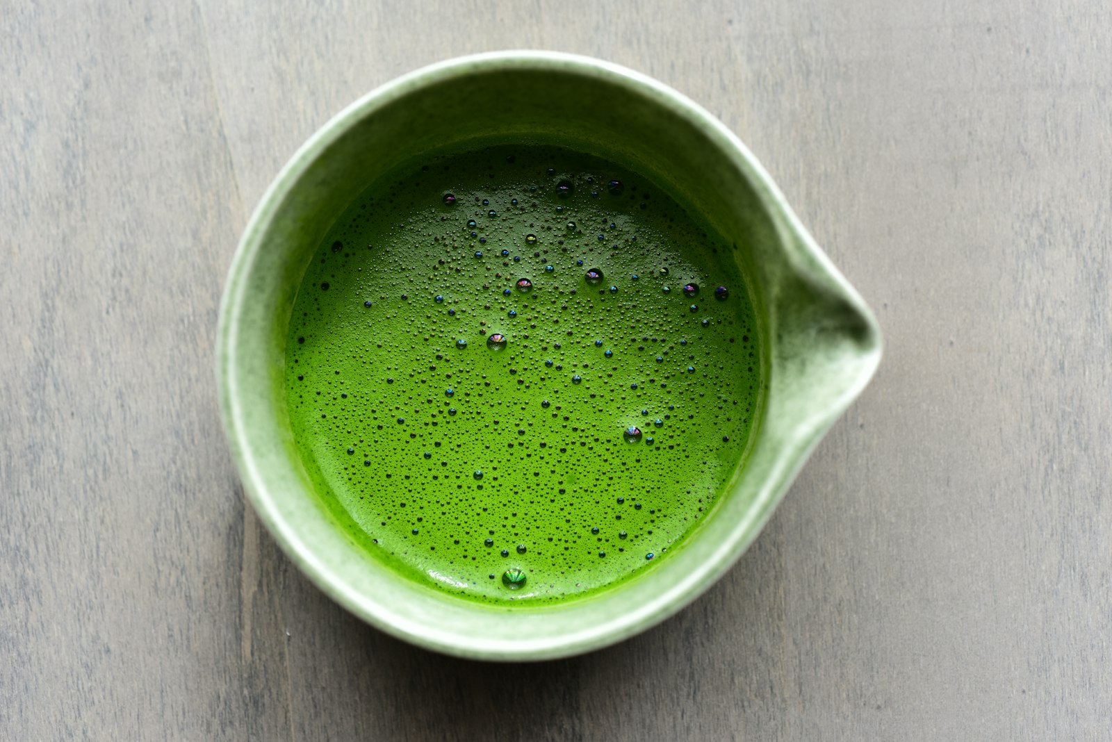 Aufgeschäumter Matcha in Schale und Tasse auf Holz: wie viel Koffein Matcha enthält