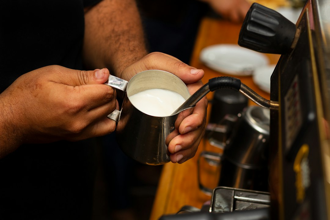 Eine Person gießt Milch in eine Tasse