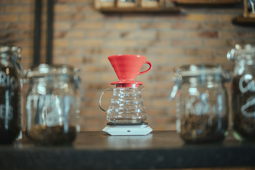 Red pour-over dripper on a glass carafe in a café in front of a brick wall