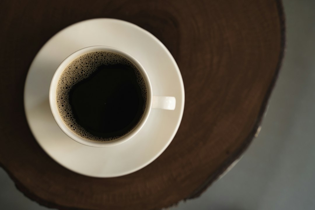 Schwarzer Kaffee in einer weißen Tasse mit Untertasse auf Holz