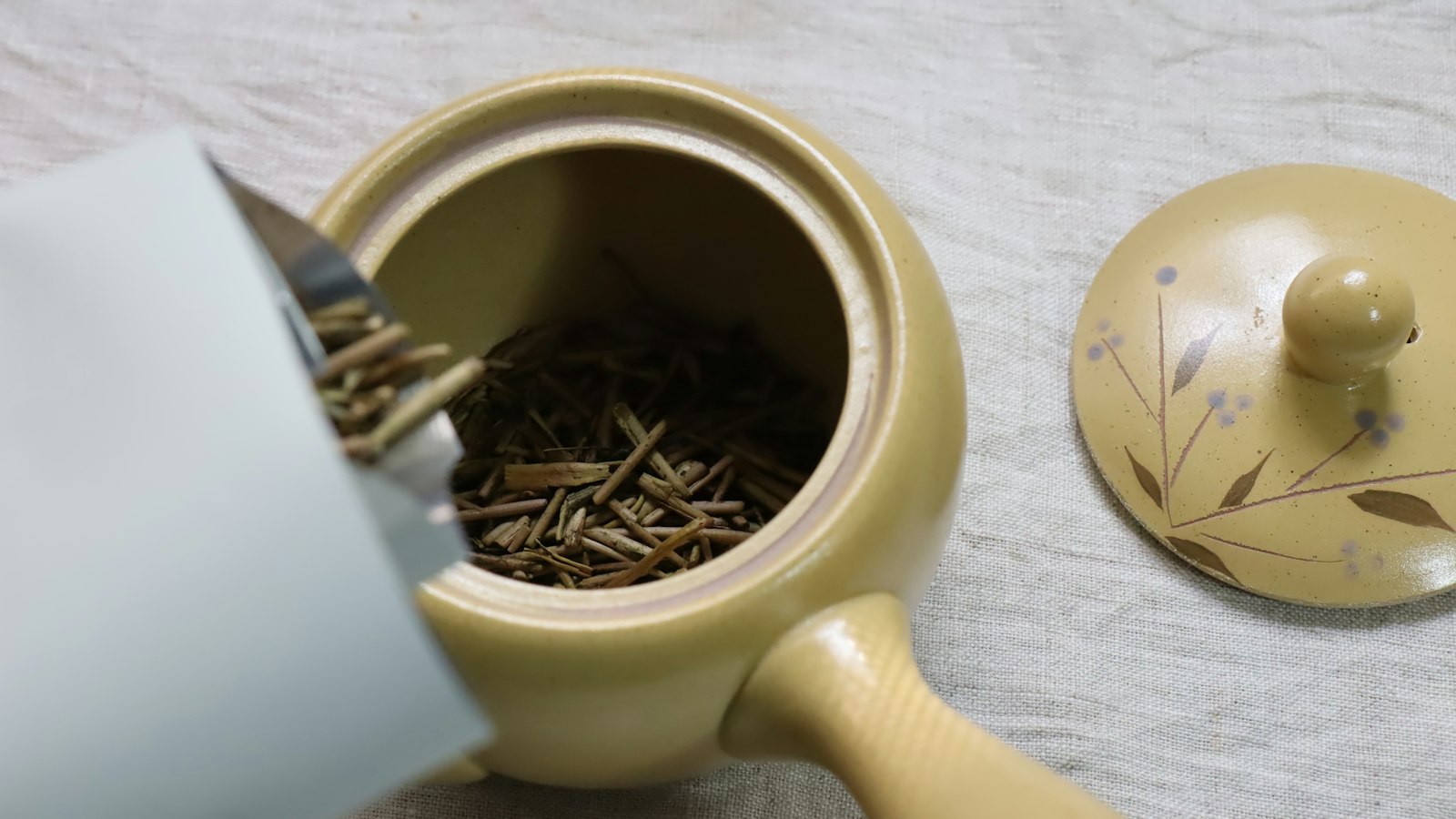 Teekanne mit Tee neben einer Tasse: Hojicha zubereiten als Blatttee oder Hojicha Latte